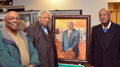 Photo by Dan Andrews. Dewey Roberts, Jr., Avon Rollins and commissioner Daniel Brown are pictured with a portrait of Rollins at the Beck Cultural Center.