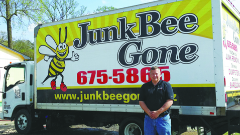 Photo courtesy of Mike Such Mike Such, owner and operator of Junk Bee Gone, stands beside on of the company trucks.
